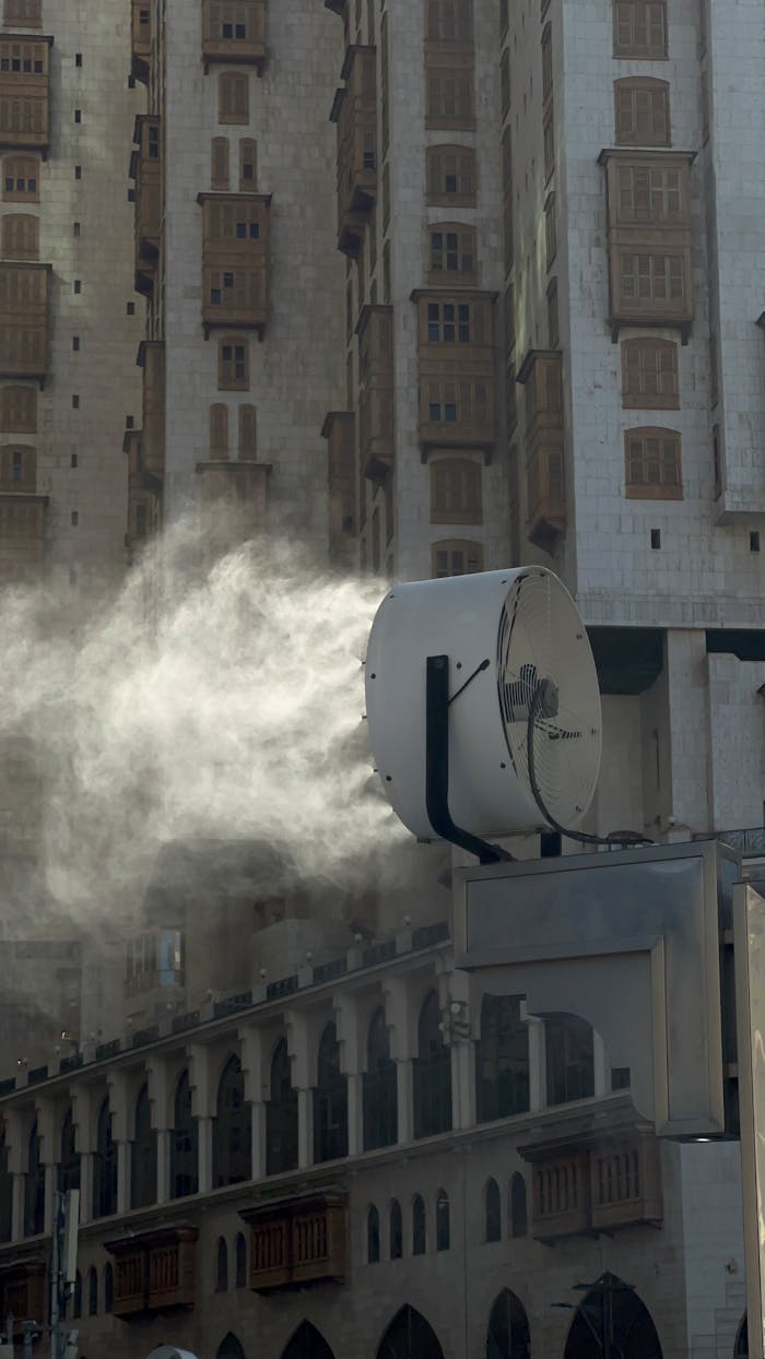 A large industrial fan spraying mist against a backdrop of urban architecture.